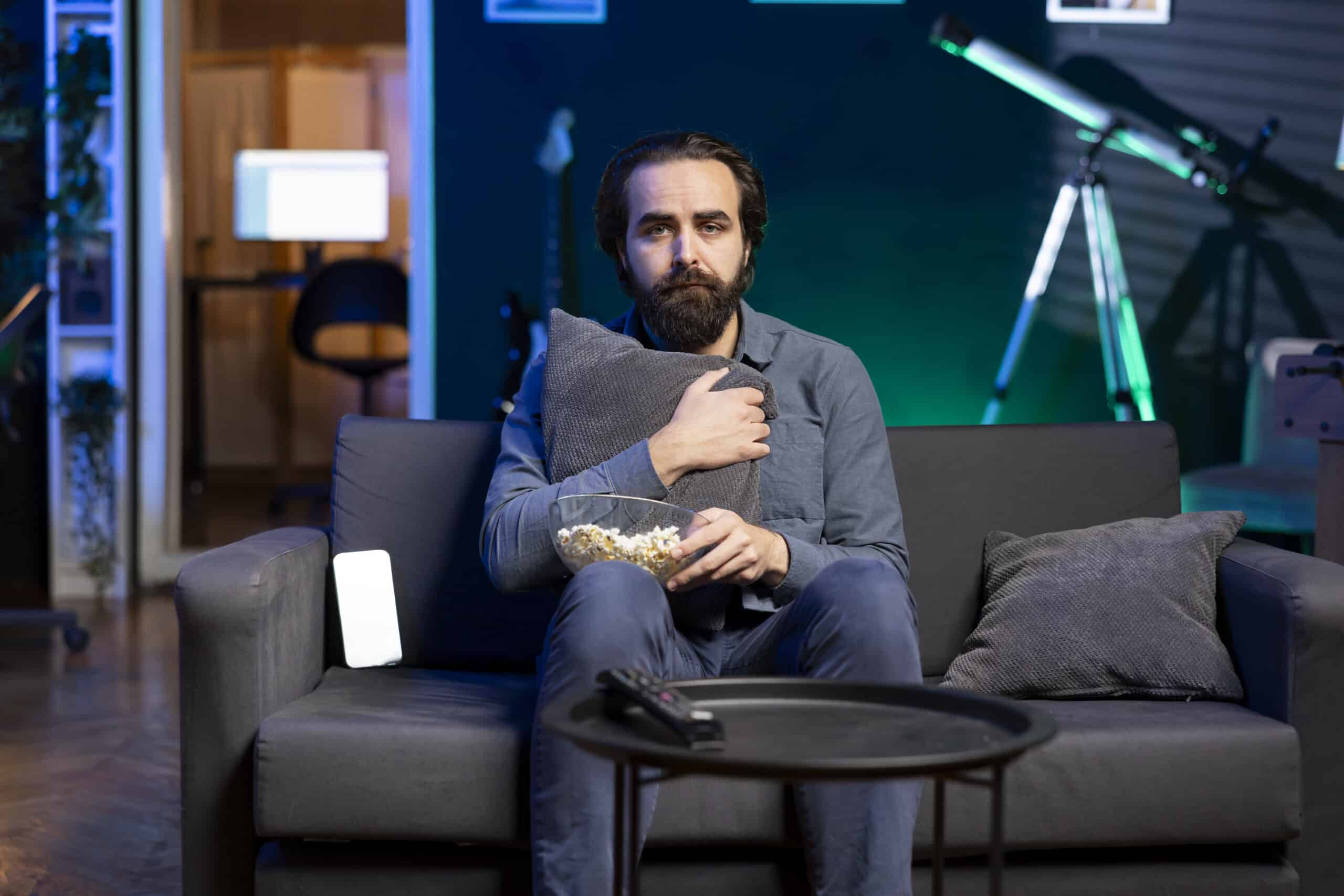Scared man hugging pillow while binging horror tv series 2363483 scaled