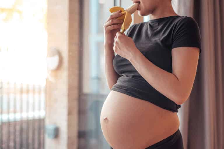 pregnant woman eating a banana after workout picjumbo com